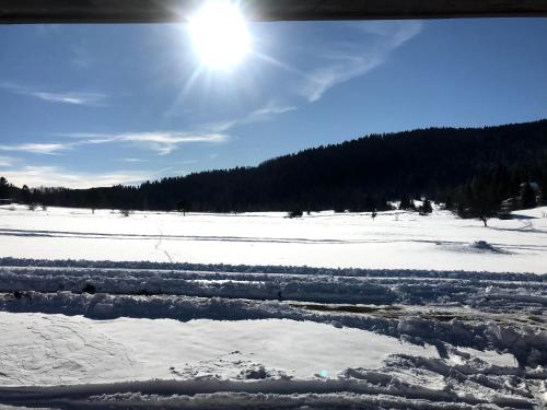 a snow covered field with the sun in the sky at Suncana dolina Tara in Kaludjerske Bare