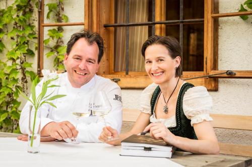 a man and a woman sitting at a table with wine glasses at Triad Wiener Alpen Bett DZ in Bad Schönau