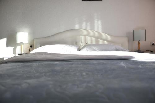 a large bed with a white headboard and two lamps at Apartman Ćorić Posušje in Posušje