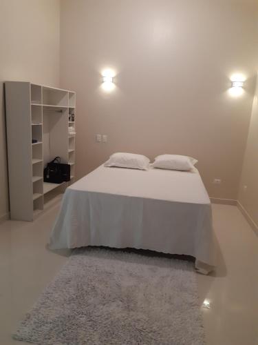 a white bedroom with a bed with two pillows and a rug at Linda casa com vista pro mar!! in Ilhabela