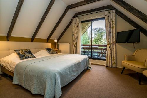 a bedroom with a bed and a window and a chair at Hostellerie Schuddebeurs in Schuddebeurs