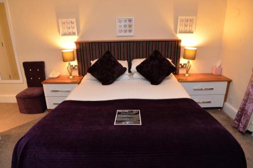 a bedroom with a large bed with black pillows at Lauriston & Lawton Court Hotel in Llandudno