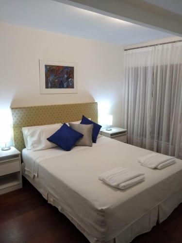 a bedroom with a large white bed with blue pillows at RIO y VERDE in Córdoba