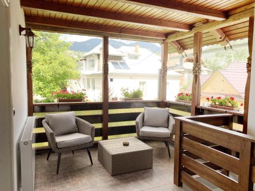 a screened in porch with two chairs and a table at Casuta Fulgu - sa te simti ca acasa! in Borşa