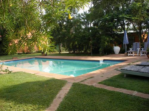 a swimming pool in a yard with a bench and trees at Gloria's Bed and Breakfast in Livingstone