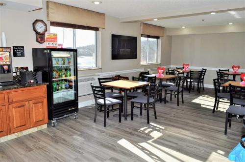 a restaurant with tables and chairs and a refrigerator at Super 8 by Wyndham Clearfield in Clearfield