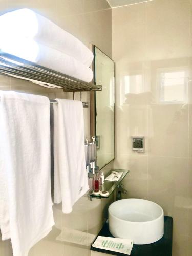 a bathroom with a white toilet and towels at CONTENTO RETREAT in Hulhumale