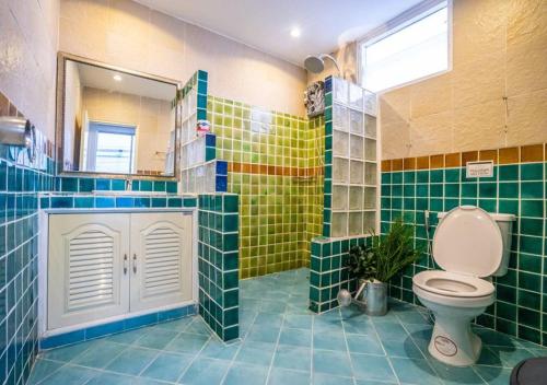 a bathroom with a toilet and green and yellow tiles at 2 Bedrooms 1 living room near Old City in Chiang Mai