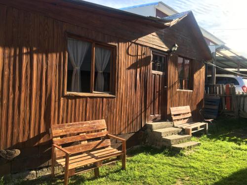 una casa de madera con un banco fuera de ella en Casa Sol y Luna en Ushuaia