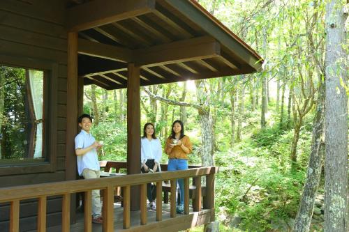three people standing on the porch of a cabin in the woods at Tateshina Tokyu Hotel in Chino