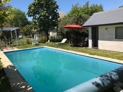 ein blauer Swimmingpool in einem Hof mit einem Haus in der Unterkunft Ngapuna Cottage in Christchurch
