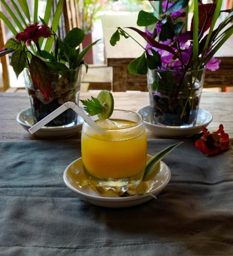 a drink on a plate on a table with flowers at The Wisma Pulau Merah in Pasanggaran