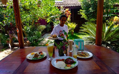 a man holding a plate of food on a wooden table at The Wisma Pulau Merah in Pasanggaran
