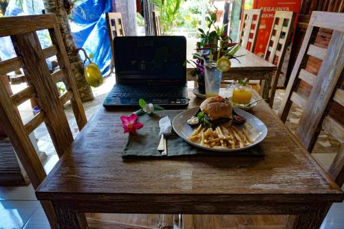 a table with a plate of food and a laptop at The Wisma Pulau Merah in Pasanggaran