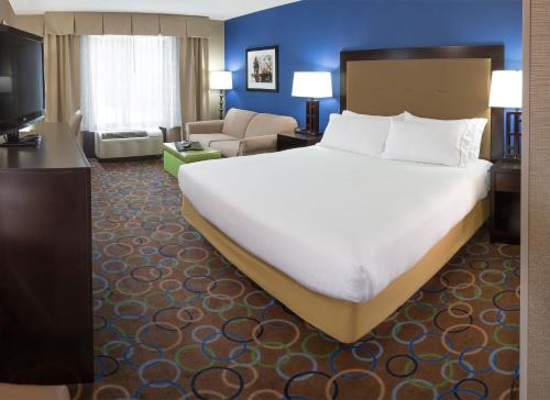 a bedroom with a large bed and a living room at Holiday Inn Express Hotel & Suites Manchester - Airport by IHG in Manchester