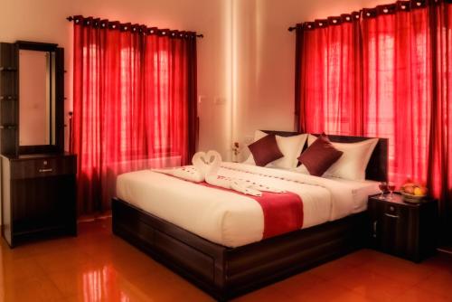 a bedroom with a large bed with red curtains at Wayanad Three Roots Holiday Home Resort in Sultan Bathery