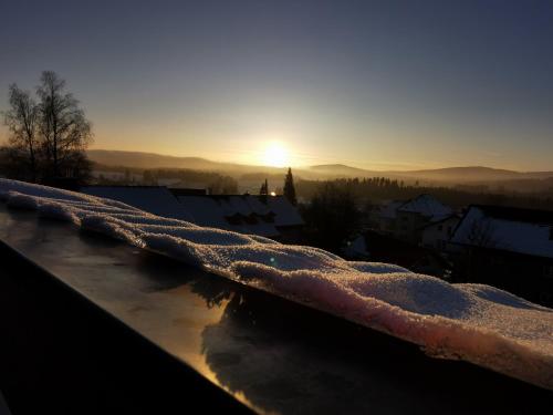 a snow covered ledge with the sunset in the background at Haus Haidweg - Ferienwohnungen in Haidmühle im Dreiländereck DE-CZ-AT in Haidmühle