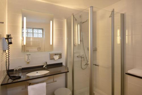 a white bathroom with a shower and a sink at Posthotel Kolberbräu in Bad Tölz