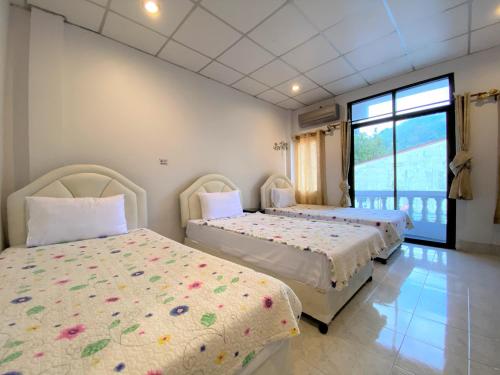 - une chambre avec 2 lits et une grande fenêtre dans l'établissement Som Guesthouse, à Patong Beach