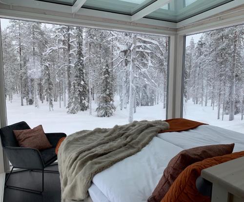 a bedroom with a bed and a window with snow covered trees at Arctic Skylight Lodge in Äkäslompolo