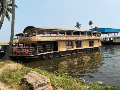 a house boat on a river with palm trees at Agape Marari in Mararikulam