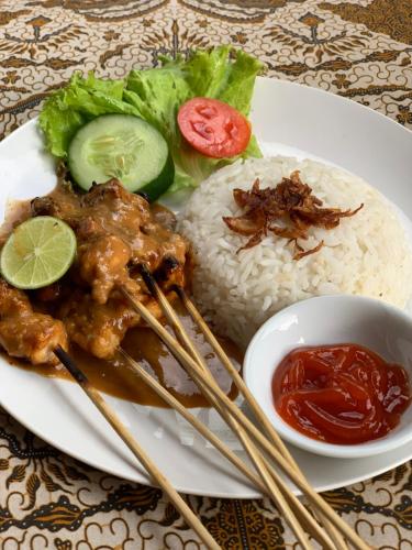 a plate of food with chicken and rice with chopsticks at Kukuh House Ubud in Ubud