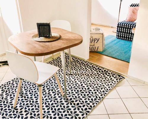 Cozy City Apartment - by Nahuen Suites في غراتس: غرفة طعام مع طاولة وكراسي على سجادة سوداء وبيضاء