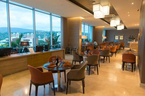 a restaurant with tables and chairs and large windows at Holiday Inn Cúcuta by IHG in Cúcuta