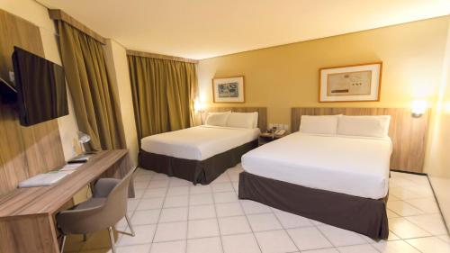a hotel room with two beds and a desk at Holiday Inn Fortaleza by IHG in Fortaleza