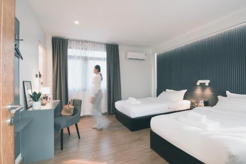 a hotel room with two beds and a person walking through the window at 41Cafetel in Bangkok