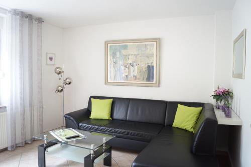 a living room with a black couch and yellow pillows at Ferienwohnung Kunkel in Kreuzau