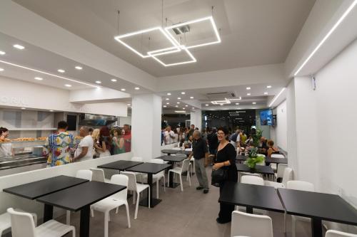 a restaurant with black tables and white chairs and people at Mediterraneo Palace Luxury Affittacamere in Pachino
