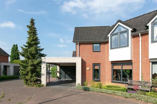 a brick house with a garage and a tree at Meenestee, Borculo in Borkulo