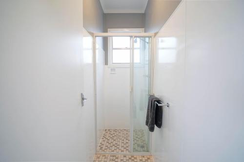 a shower with a glass door in a bathroom at The Platypus Accommodation & Cafe in Cudal