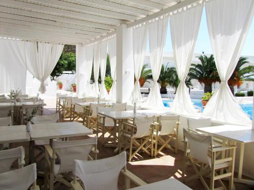 Porto Scoutari Romantic Hotel في سكالا: مطعم بطاولات بيضاء وكراسي ومسبح