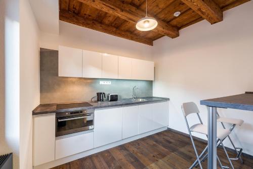 a kitchen with white cabinets and a table at Modern Apartment in a Picturesque 15th-Century Building in Prague
