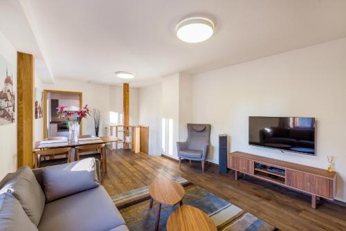 a living room with a couch and a flat screen tv at Modern Apartment in a Picturesque 15th-Century Building in Prague