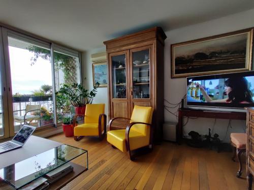 d'un salon avec des chaises jaunes et une télévision à écran plat. dans l'établissement Paris On Top, à Paris