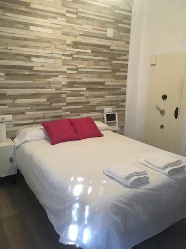 1 dormitorio con cama blanca y pared de madera en Apartamento con barbacoa BBQ Los picadores, en Córdoba