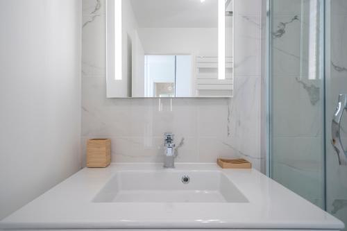 a white bathroom with a sink and a mirror at Les terrasses in Fontenay-aux-Roses