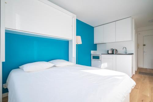 Cette chambre comprend un grand lit blanc et un mur bleu. dans l'établissement Les terrasses, à Fontenay-aux-Roses