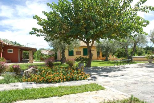 un jardín con un árbol y flores frente a una casa en Case Di Loco Castro, en Agnone Bagni