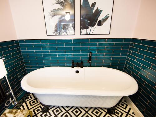 a bath tub in a bathroom with blue tiles at Luxury Travel Emporium HG1 - 2 Luxury apartments with Parking Space - in town centre in Harrogate
