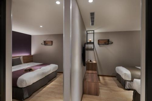 a hotel room with two beds and a mirror at Muzik Hotel - Ximen Station Branch in Taipei