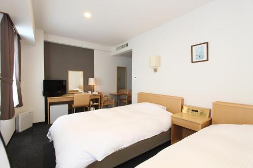 a hotel room with two beds and a desk at Smile Hotel Yonezawa in Yonezawa