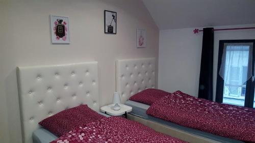 1 dormitorio con 2 camas y almohadas rojas en Loc'apparts, en Beaumont-sur-Oise