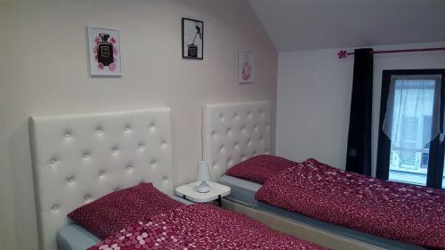 a bedroom with two beds with red pillows at Loc'apparts in Beaumont-sur-Oise