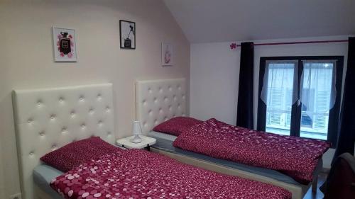 Un dormitorio con una cama con almohadas rojas y una ventana en Loc'apparts en Beaumont-sur-Oise