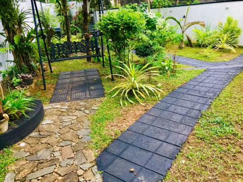 a walkway in a garden with plants and a fence at Travellers Halt in Ratnapura
