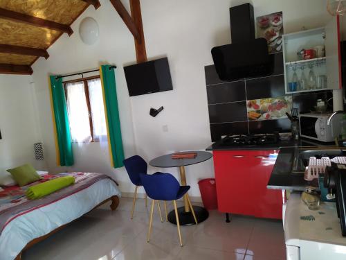 a small kitchen with a bed and a table and chairs at Le Cyprès in Cilaos